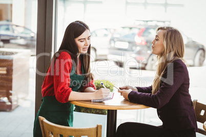 Cute blonde girl ordering from her friend