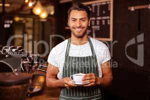 Smiling barista holding coffee