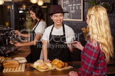 Smiling waiter serving a coffee to a customer