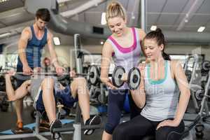 Trainer woman helping woman lifting dumbbell