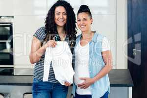 Portrait of lesbian couple holding babys clothes