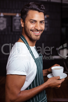 Smiling barista holding coffee