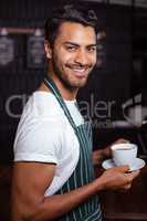 Smiling barista holding coffee