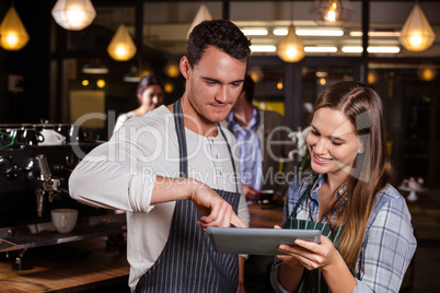 Smiling baristas using tablet