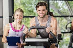 Trainer woman with a man doing exercise bike