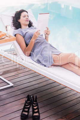 Young woman reading magazine near poolside