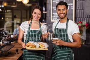 Smiling baristas holding sandwiches and hot milk