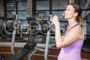 Smiling pregnant woman drinking water