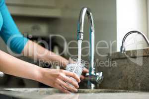 Pretty blonde woman filling a glass of water