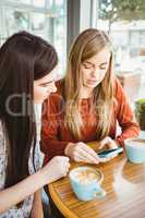 Friends using smartphone and having coffee