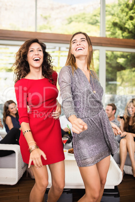 Two women dancing and group of friends watching their dance