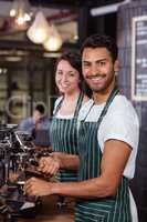 Smiling baristas using coffee machine