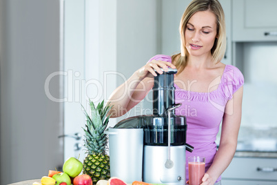 Blonde woman preparing a smoothie in the kitchen