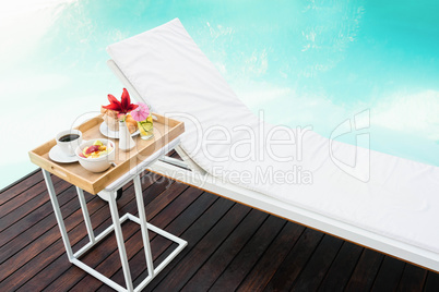 Tray with breakfast in side table and sun lounger