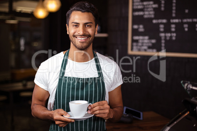 Smiling barista holding coffee