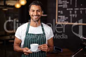 Smiling barista holding coffee