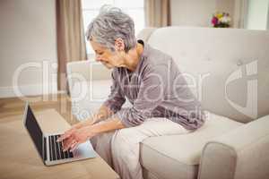 Senior woman using laptop in living room