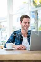 Handsome man working on laptop with cup of coffee