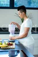 Pregnant woman preparing fruit juice in blender
