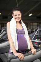 Smiling pregnant woman standing on treadmill