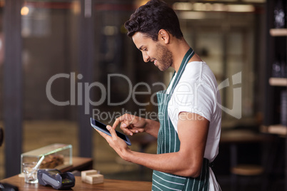 Smiling barista using tablet