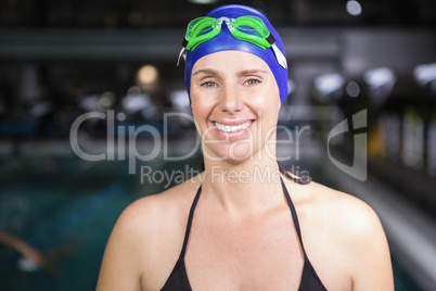 Smiling pregnant woman standing next to the pool