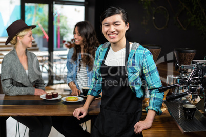 Smiling waiter in apron behind the counter