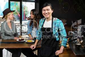 Smiling waiter in apron behind the counter