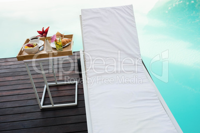 Tray with breakfast in side table and sun lounger