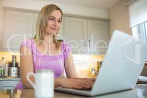 Pretty blonde woman having coffee and using laptop