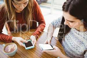 Friends using smartphone and having coffee