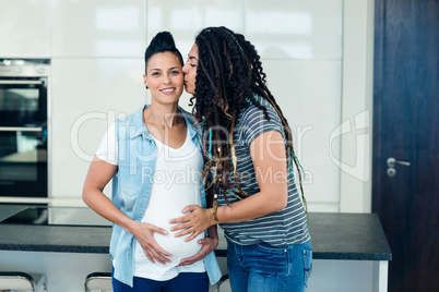 Woman kissing her pregnant partner