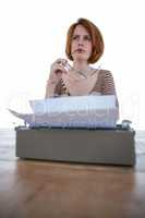 hipster woman thinking in front of her typewriter