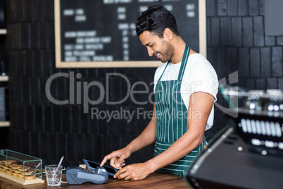 Handsome barista using cash register