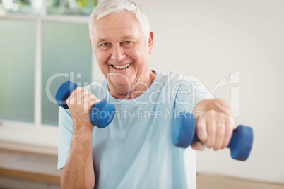 Portrait of senior man exercising with dumbbells