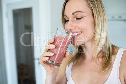 Pretty blonde woman holding her homemade smoothie