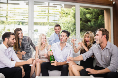 Man popping champagne bottle with friends