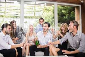 Man popping champagne bottle with friends