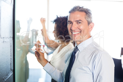 Businesspeople writing on white board