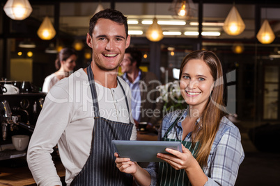 Smiling baristas using tablet