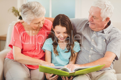 Grandparents reading a book with granddaughter