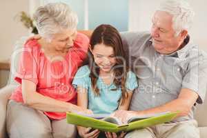 Grandparents reading a book with granddaughter