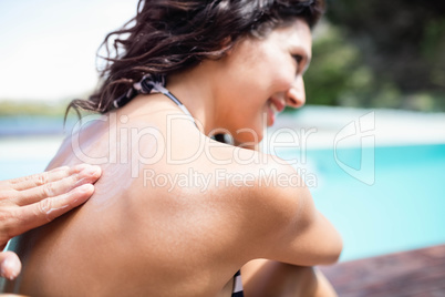 Man applying sunscreen on back of her womanÂ 