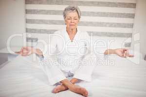 Senior woman meditating on bed