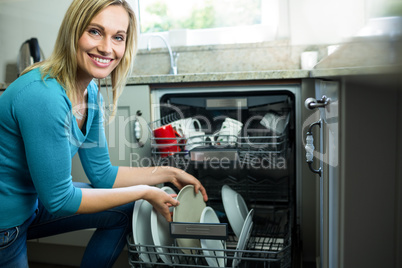 Pretty blonde woman emptying the dishwasher
