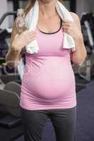 Pregnant woman standing next to exercise bike