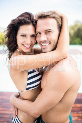 Young couple cuddling each other near pool