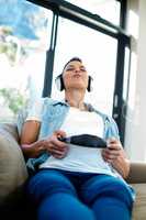 Pregnant woman listening to music on sofa