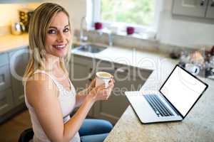 Pretty blonde woman having coffee and using laptop