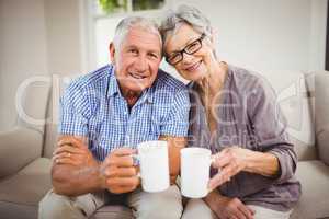 Senior couple having coffee in living room